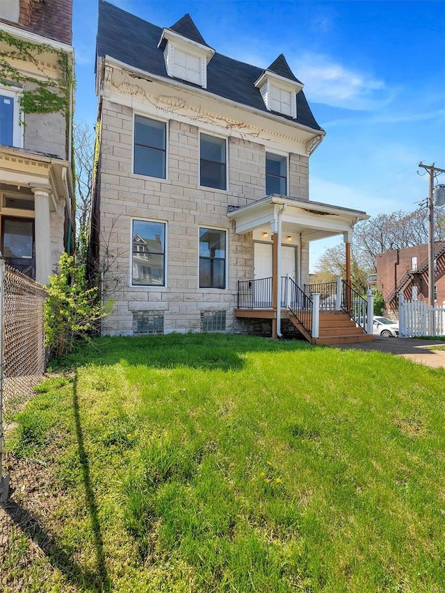 view of front of home featuring fence, a porch, a front yard, and stone siding