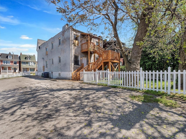 view of side of property featuring stucco siding, stairway, a deck, and fence private yard