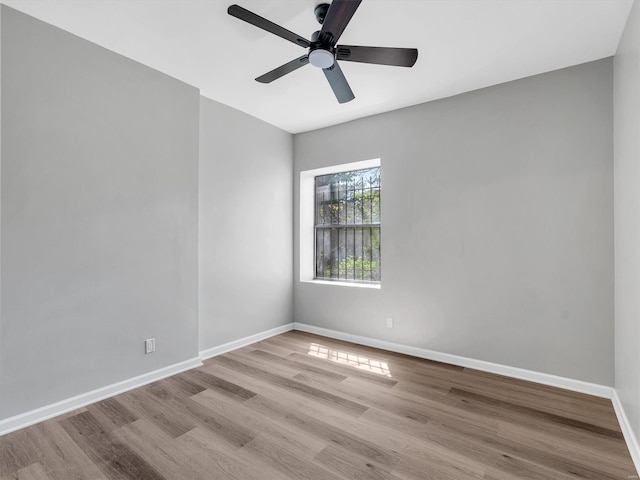 spare room with baseboards, wood finished floors, and a ceiling fan