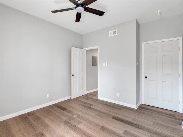 unfurnished bedroom with ceiling fan, electric panel, light wood-type flooring, visible vents, and baseboards