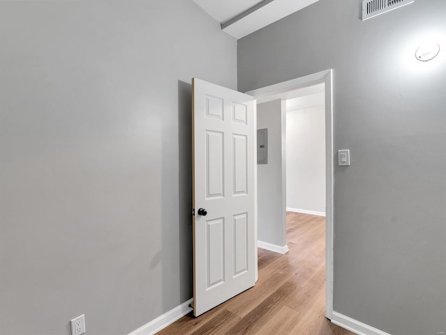 spare room with wood finished floors, visible vents, electric panel, and baseboards