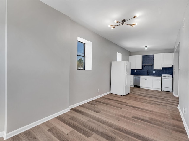 kitchen featuring white appliances, light wood-style floors, a sink, white cabinetry, and a notable chandelier