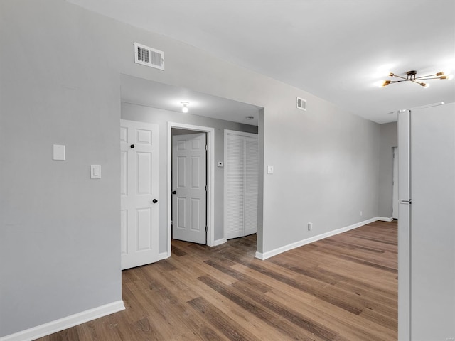 empty room featuring wood finished floors, visible vents, and baseboards