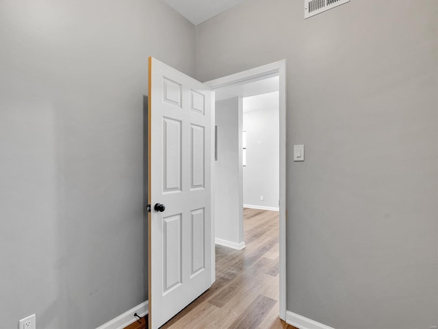 corridor with baseboards, visible vents, and light wood-style floors