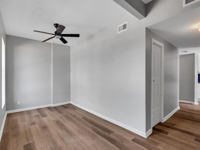 empty room featuring visible vents, ceiling fan, wood finished floors, and baseboards