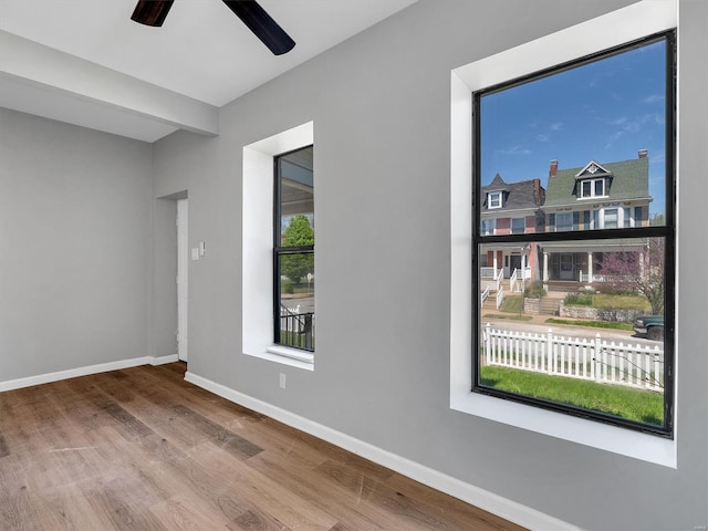 spare room with wood finished floors, a ceiling fan, and baseboards