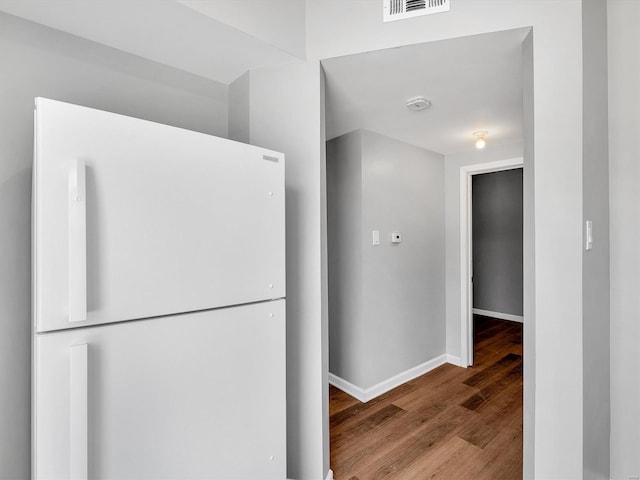 hall featuring visible vents, wood finished floors, and baseboards