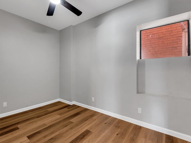 spare room with wood finished floors, ceiling fan, and baseboards
