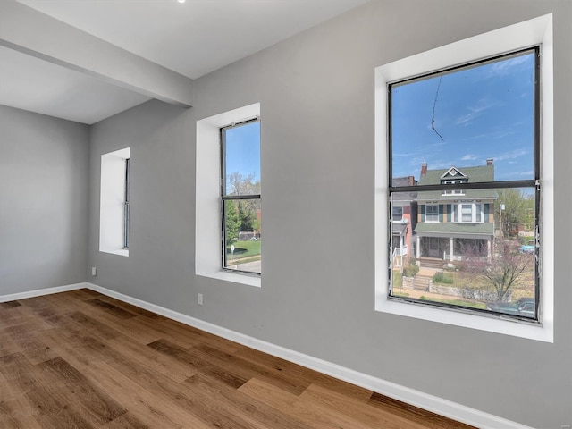 empty room with baseboards, wood finished floors, and a wealth of natural light