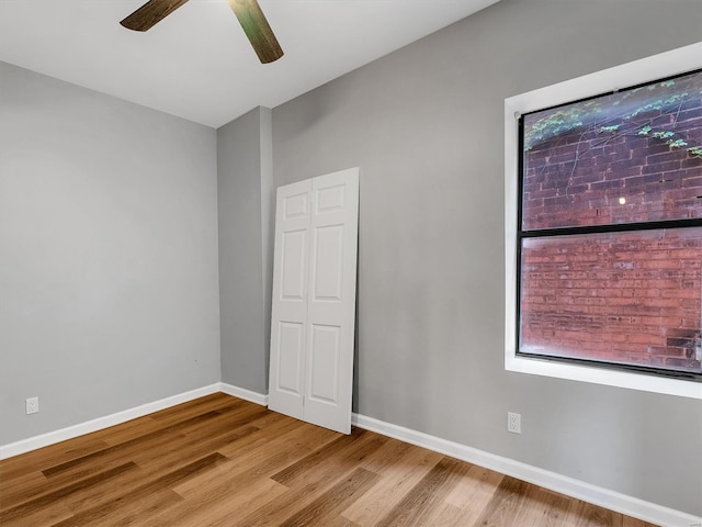 empty room featuring baseboards, wood finished floors, and a ceiling fan