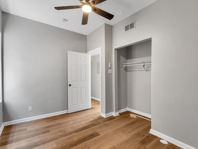 unfurnished bedroom featuring baseboards, visible vents, wood finished floors, and a closet