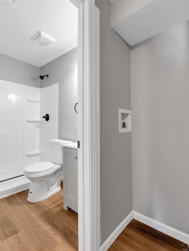 bathroom featuring vanity, toilet, baseboards, walk in shower, and wood finished floors