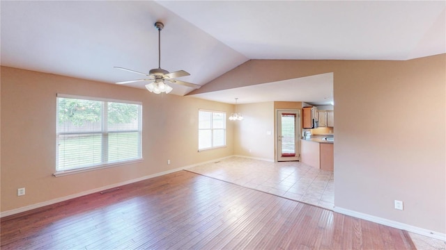 unfurnished living room with lofted ceiling, visible vents, baseboards, light wood-type flooring, and ceiling fan with notable chandelier
