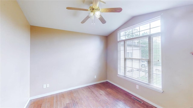 spare room featuring ceiling fan, wood finished floors, visible vents, baseboards, and lofted ceiling