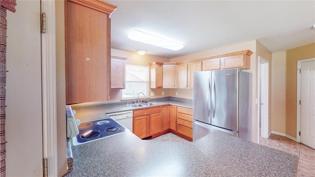 kitchen featuring a sink, white dishwasher, freestanding refrigerator, light brown cabinetry, and a peninsula