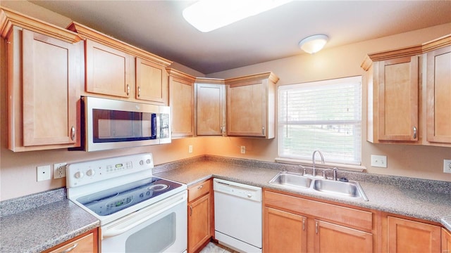 kitchen featuring white appliances, light brown cabinets, and a sink
