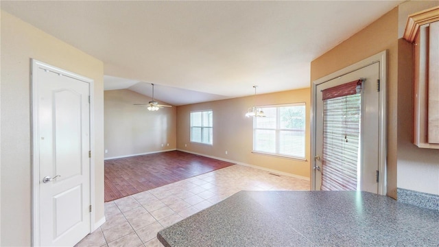 unfurnished room with light tile patterned floors, baseboards, vaulted ceiling, and ceiling fan with notable chandelier