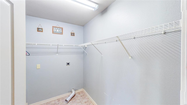 laundry area featuring tile patterned floors, electric dryer hookup, laundry area, and baseboards