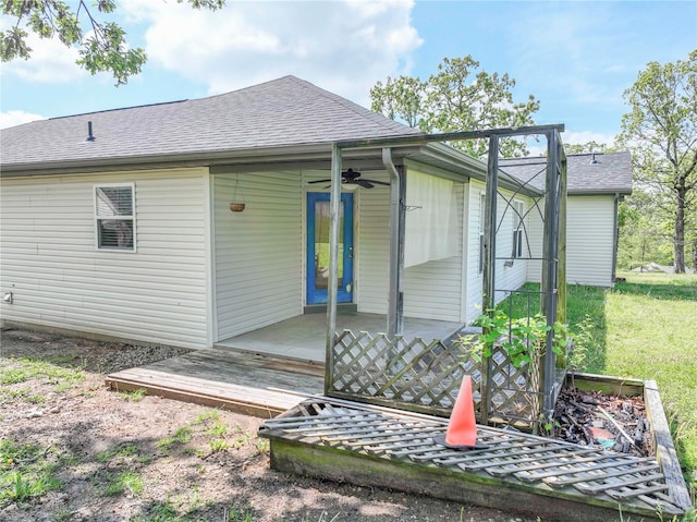 back of property featuring a ceiling fan and a shingled roof