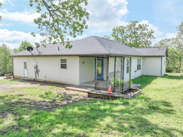 back of property with a lawn and a shingled roof