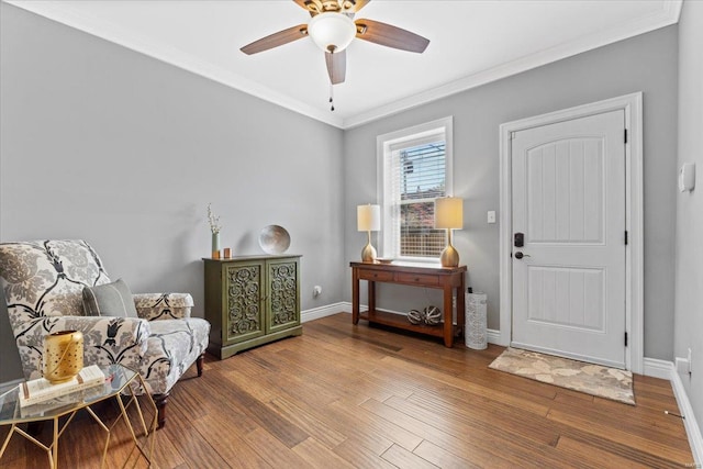 sitting room featuring a ceiling fan, baseboards, ornamental molding, and wood finished floors