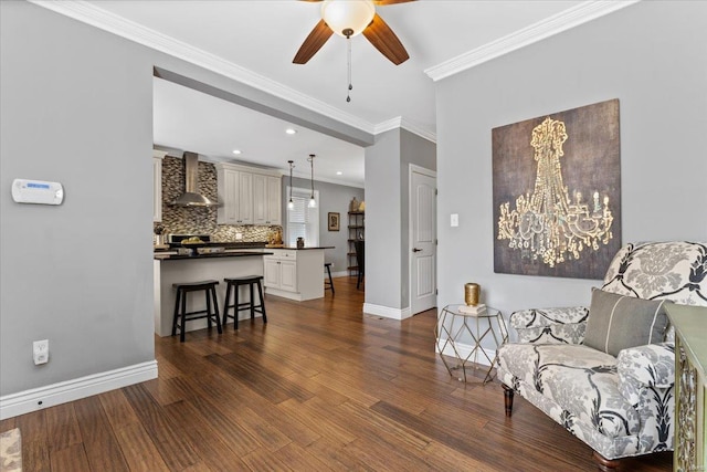 sitting room with ceiling fan, baseboards, crown molding, and dark wood-style floors