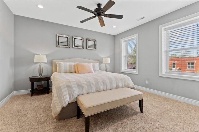 bedroom with baseboards, visible vents, light colored carpet, and ceiling fan