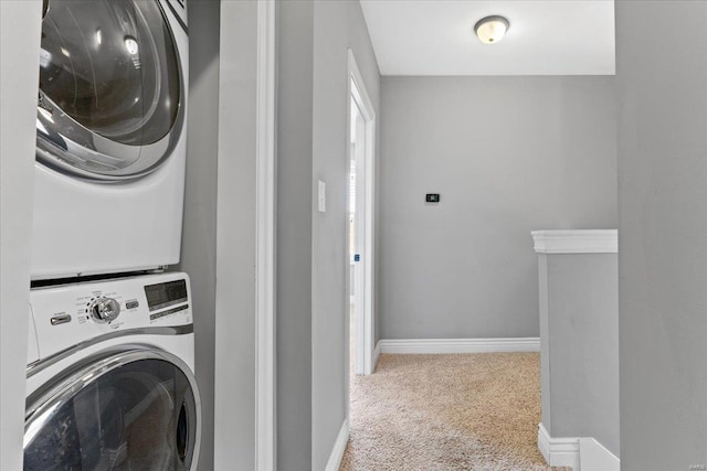 washroom featuring baseboards, stacked washer / drying machine, laundry area, and carpet
