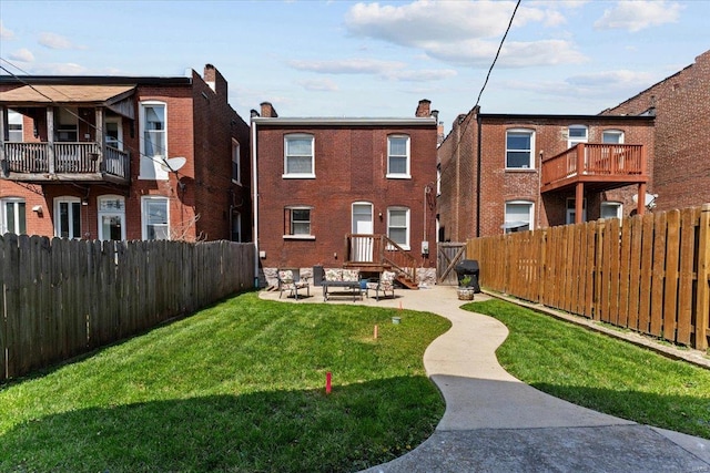 rear view of house with a fenced backyard, brick siding, and a yard
