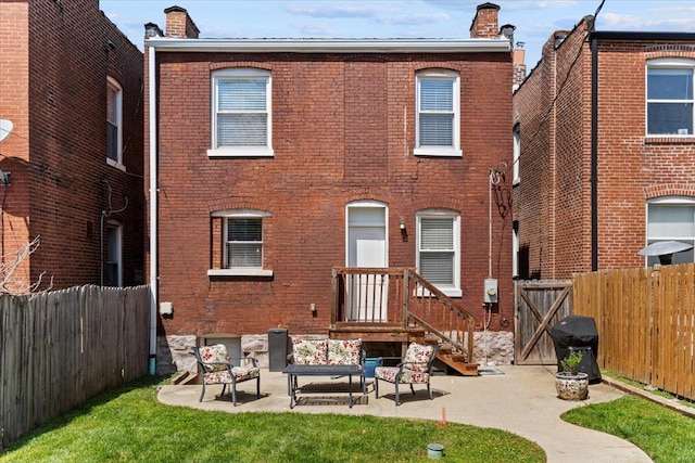back of property with outdoor lounge area, a chimney, a fenced backyard, a patio area, and brick siding