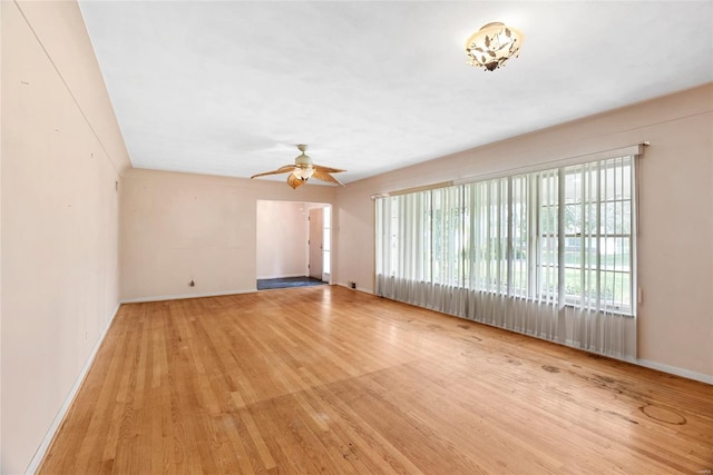 empty room featuring baseboards, wood finished floors, and a ceiling fan