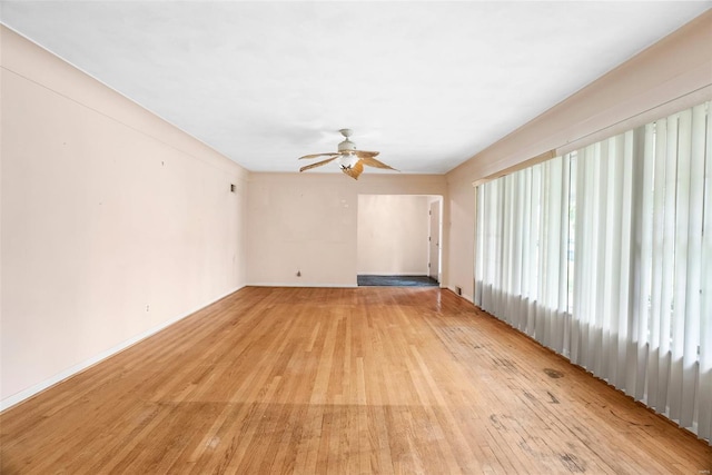unfurnished living room featuring baseboards, light wood-type flooring, and ceiling fan