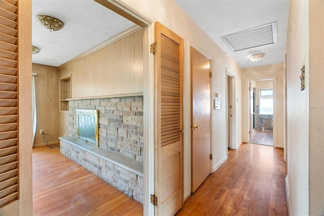 hallway featuring baseboards, visible vents, wood finished floors, and ornamental molding