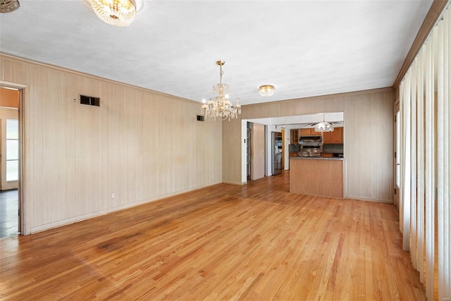 unfurnished living room featuring visible vents, a chandelier, crown molding, and light wood finished floors