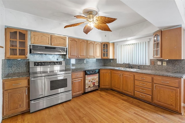 kitchen with a sink, under cabinet range hood, range with two ovens, brown cabinetry, and dishwasher
