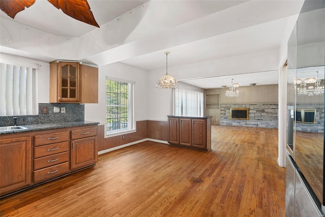 kitchen with a sink, light wood-style flooring, a notable chandelier, and brown cabinets