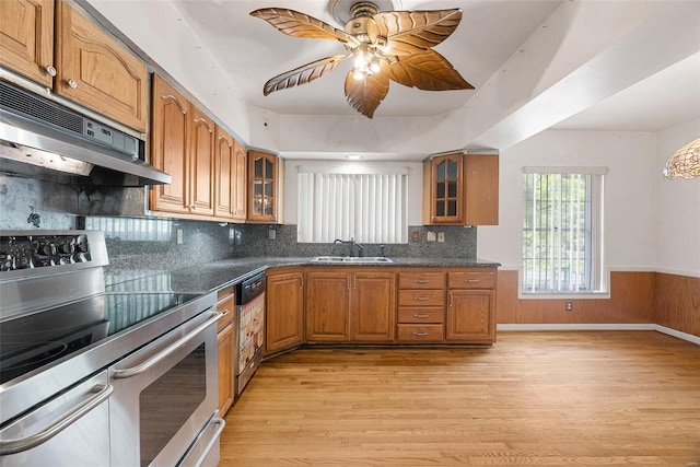 kitchen with double oven range, light wood finished floors, brown cabinetry, and a sink