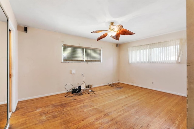 empty room featuring visible vents, wood finished floors, a healthy amount of sunlight, and a ceiling fan