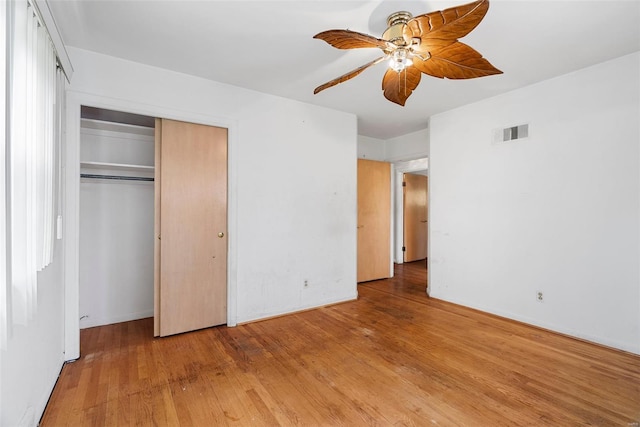 unfurnished bedroom featuring a closet, ceiling fan, visible vents, baseboards, and wood finished floors