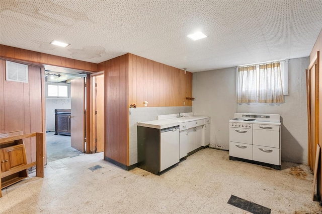 kitchen with wooden walls, light countertops, white appliances, and light floors