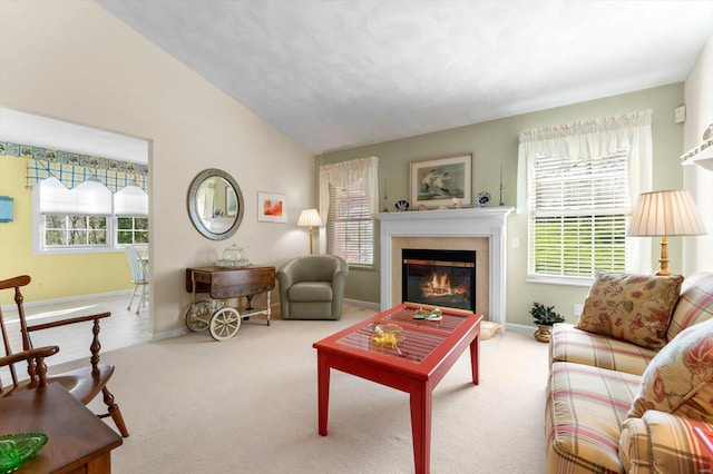 carpeted living area with lofted ceiling, baseboards, and a glass covered fireplace