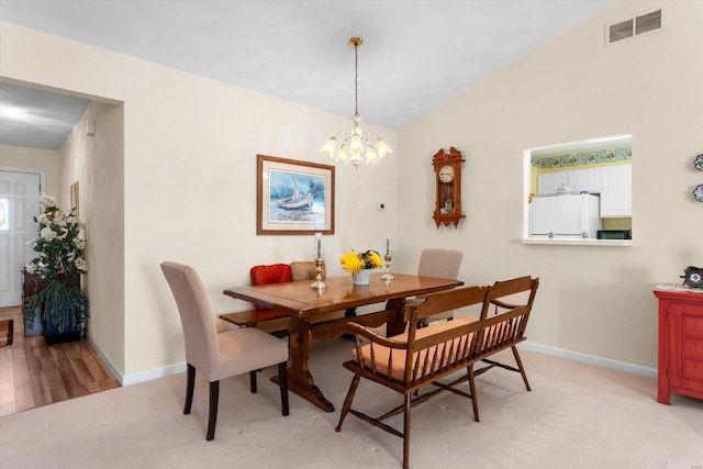 dining room featuring light colored carpet, baseboards, a notable chandelier, and visible vents