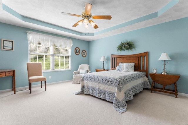 carpeted bedroom featuring baseboards, a ceiling fan, and a tray ceiling