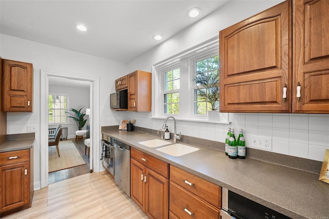 kitchen with brown cabinetry, a sink, a healthy amount of sunlight, and stainless steel appliances