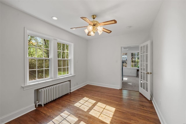 unfurnished room featuring ceiling fan, french doors, radiator, baseboards, and wood finished floors