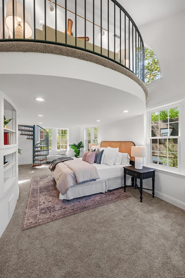 bedroom with a high ceiling, multiple windows, baseboards, and carpet