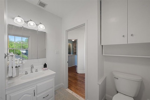 bathroom featuring decorative backsplash, visible vents, vanity, baseboards, and toilet
