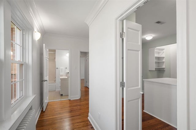 hallway with visible vents, ornamental molding, baseboards, radiator heating unit, and dark wood finished floors