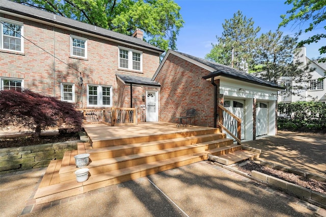 back of property featuring brick siding, a chimney, and a wooden deck