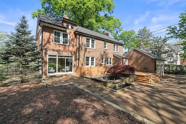 back of house featuring brick siding, a patio area, and a chimney